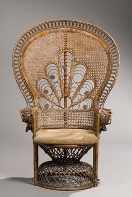 an antique wicker chair with a beige cushion on top of it