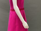 the mannequin is wearing a bright pink dress with a red belt