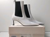 des bottines en cuir blanc posées sur une boîte avec un fond blanc