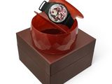 une montre posée sur une boîte, sur une surface blanche