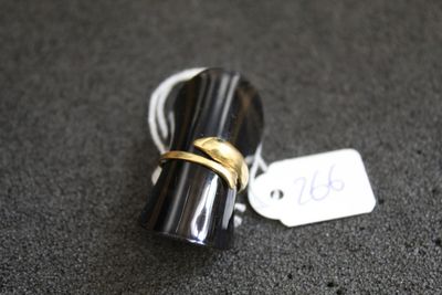 une photo d'une bague noire et dorée à laquelle est accrochée une étiquette