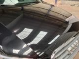 a black car parked in a parking lot next to a fence