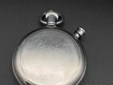 a silver pocket watch sitting on a black surface