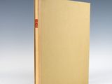 un livre à la couverture dorée posé sur une surface blanche