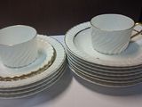 two cups and a saucer on top of a stack of plates