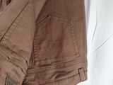 brown pants hanging on a hanger in front of a white curtain