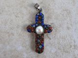 a close up of a cross with a pearl in the center