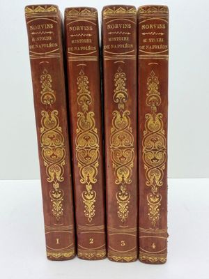 quatre vieux livres sont alignés sur une surface blanche