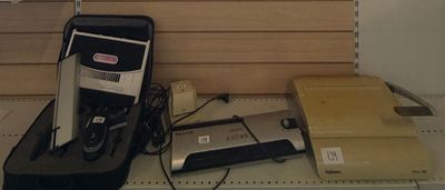 une photo montrant une valise et d'autres appareils électroniques posés sur une étagère