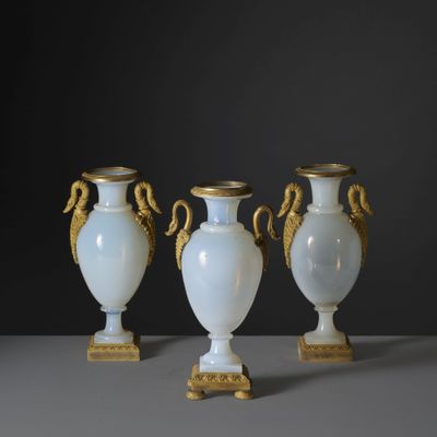 trois vases blancs aux anses dorées posés sur une table