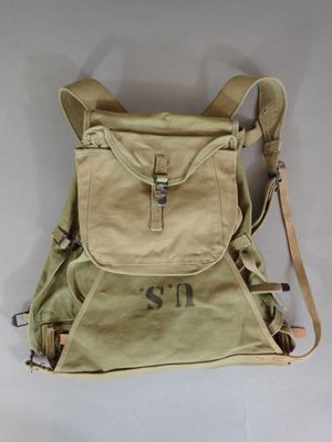 beige canvas backpack with initials on the front and shoulder straps