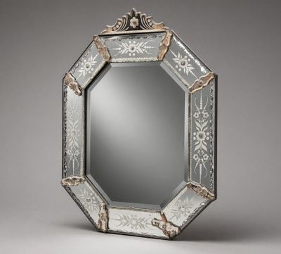 an ornately decorated mirror with a silver frame on a gray background