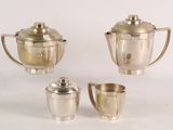 three silverplated teapots and cups on a white surface