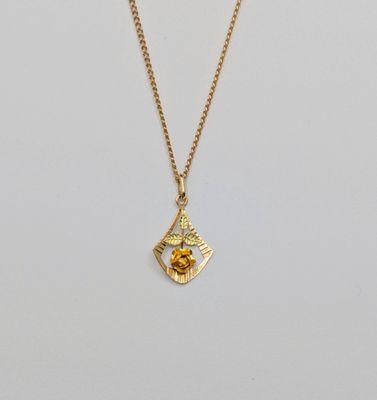 un collier plaqué or orné d'une petite fleur jaune suspendue à une chaîne