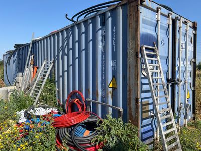 un conteneur bleu sur lequel est posée une échelle