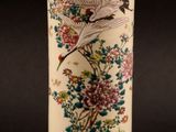 a tall vase with a bird and flowers on it