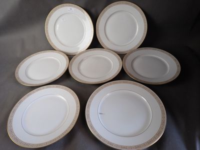 six white plates with gold rims are arranged on a table
