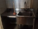 a kitchen with a sink and a trash can in it