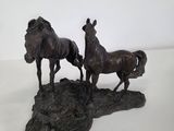 statue of three horses standing on a rock on a white surface
