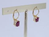 pair of gold and ruby earrings on a stand