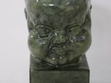 a small green statue of a man with a face on it