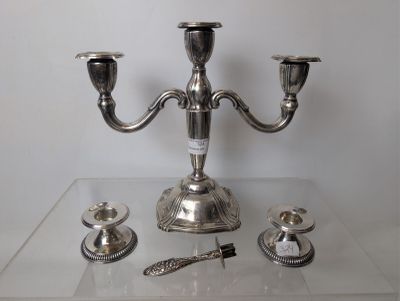 a silver candelab with three candles on a clear table