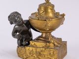 an antique bronze figurine of a boy with a bowl of fruit