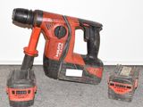 une perceuse filaire et deux batteries posées par terre