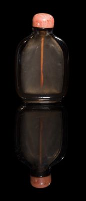 a small glass bottle with a pink top on a black surface