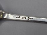 a silver spoon with a silver handle on a gray surface