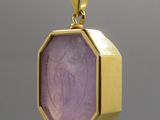 un gros plan d'un pendentif en or serti d'une pierre violette