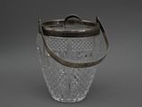 a glass ice bucket with a metal handle on a gray background