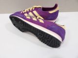 purple and gold adidas sneakers on a white surface with a white background