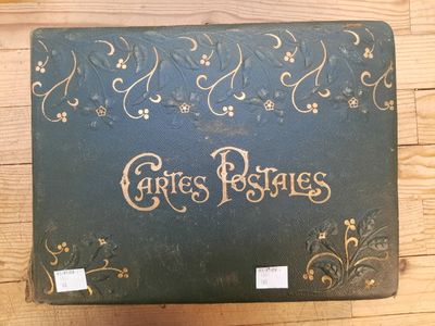 une valise verte ornée d'une inscription dorée, posée sur un plancher en bois