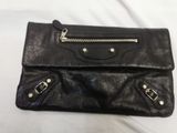 a close up of a black leather purse on a white surface