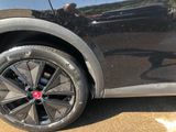 a close up of a car ' s wheel with a reflection of a man in the background