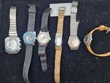 quatre montres différentes dans un écrin noir, posées sur un fond noir