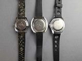 three watches are lined up in a row on a gray surface