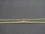 un gros plan d'un collier de perles dorées posé sur une surface noire
