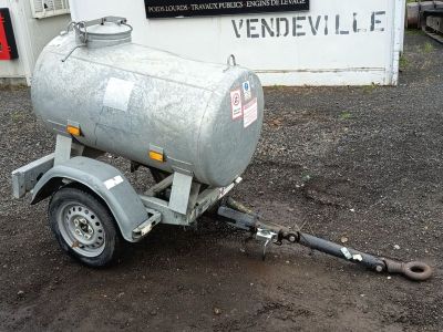 une remorque à laquelle est attelée une citerne, garée devant un bâtiment