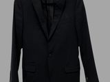 a black suit hanging on a hanger on a gray wall
