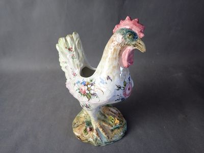 porcelain figurine of a rooster on a stand on a gray background