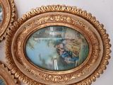 three ornate gold frames with paintings on them hanging on the wall