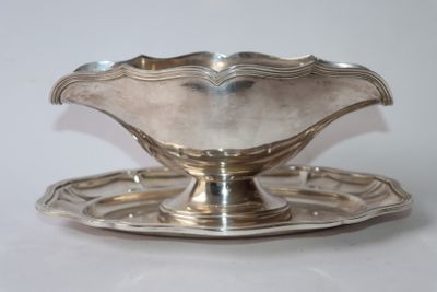 une assiette en argent posée sur une soucoupe, le tout sur une surface blanche
