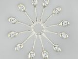 six silver spoons arranged in a circle on a gray surface