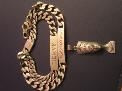 a gold chain and a silver bracelet on a black surface