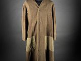 a brown coat on a mannequin stand against a black background