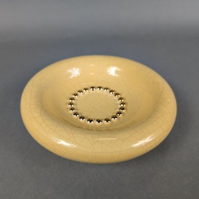 beige ceramic bowl with beaded rim on gray surface