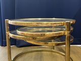 a round brass coffee table with glass top on a wooden floor