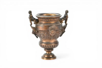 a bronze vase that is sitting on a white surface
